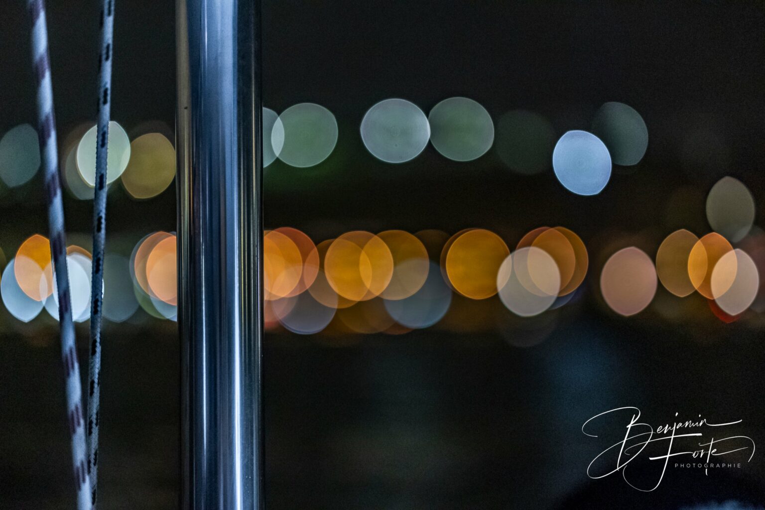 Night lights in bokeh behind a stainless rail and lines