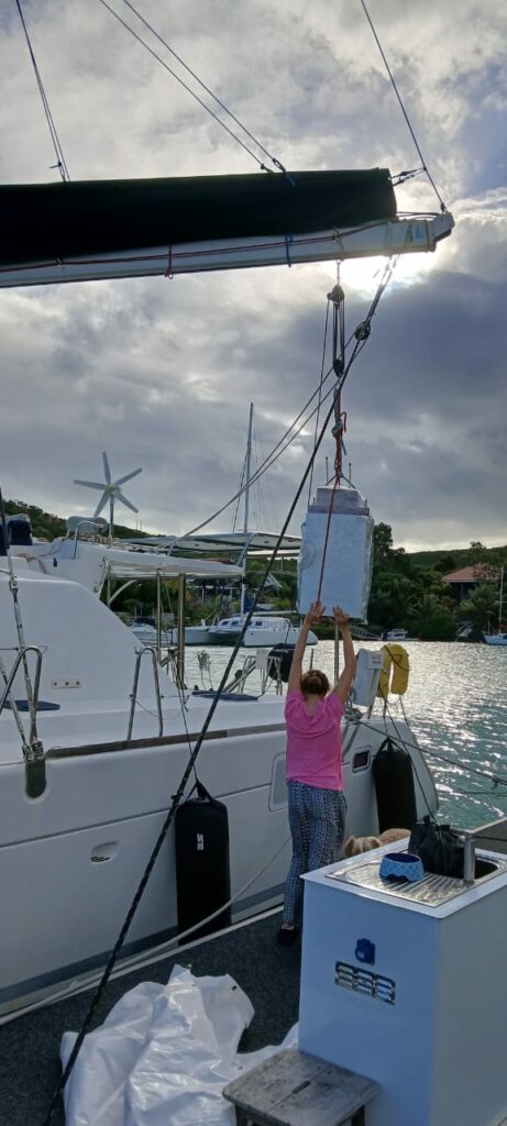 A crew member working on deck, with the mast and wind generator behind her
